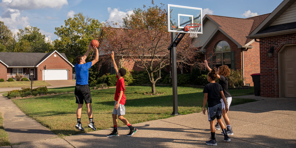 Picture of four youths playing basketball outside of home, using Goalrilla Basketball hoop