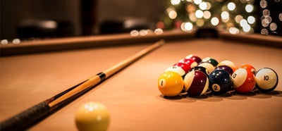 Close-up of Billiard Table With Pool Cue and Balls with Holiday Lights in Background - The Great Escape